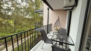 a balcony with a glass table and chairs on it at Sun Estate Ureki in Ureki
