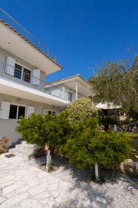 a white house with trees in front of it at La Sirenetta Residence in Syvota