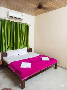 a bedroom with a large bed with a green curtain at Caffe Bombay in Nagaon