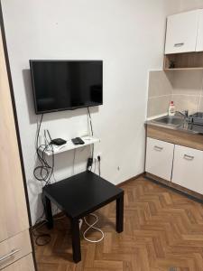 a small kitchen with a table and a flat screen tv at Novosadska Tvrdjava Apartments in Petrovaradin