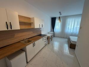 a kitchen with white cabinets and a living room at Ayan Studio - Băile Felix in Sînmartin