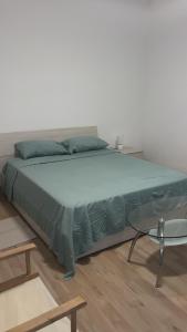 a bed with a green comforter and a table at Casa Vacanza Giorgio Apartment in Gallarate