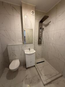 a white bathroom with a toilet and a sink at Ayan Studio - Băile Felix in Sînmartin