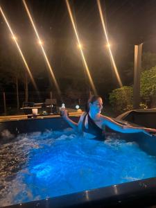 a woman in a swimming pool at night at LODKA Vendégház in Szigetcsép