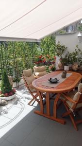 a patio with a wooden table and chairs under a white canopy at B&B Grace in Villa Opicina