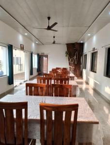 a dining room with wooden tables and chairs at Rainbow Cottage Stays in Kānha