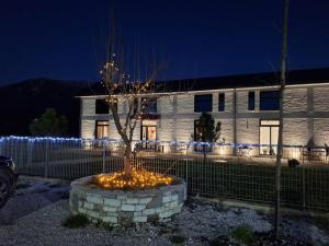 a tree in a pot with lights in front of a building at Lumi i Bardhe Hotel & Restaurant in Kuç