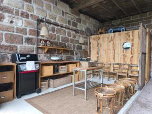 a kitchen with a table and stools and a brick wall at Le Tilleul d'Hortense in Ussac