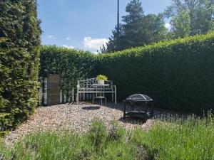 a table and chairs in a garden with a hedge at Apartmán Kathryn in Dubá