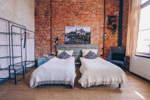 two beds in a room with a brick wall at Old Post Loft Apartments in Spremberg