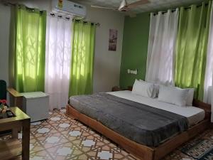 a bedroom with a large bed with green curtains at Immanuel Victory hotel in Atebubu