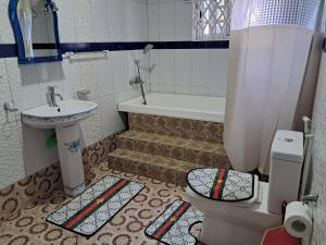 a bathroom with a toilet and a sink and a tub at Immanuel Victory hotel in Atebubu