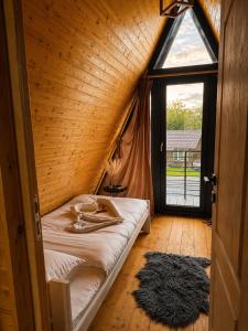 ein Bett in einem Holzzimmer mit großem Fenster in der Unterkunft Ocna Frame - A Frame cu Jacuzzi si Terasa in Ocna-Mureşului