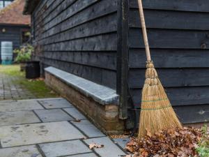 a broom leaning against the side of a house at Quarter Cottage in Biddenden