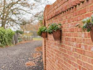 a brick wall with two potted plants on it at Quarter Cottage in Biddenden