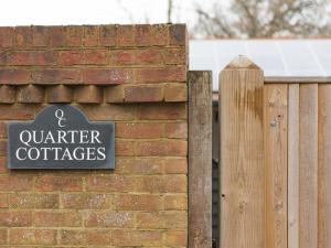a sign on a brick wall next to a fence at Quarter Cottage in Biddenden