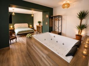 a large bath tub in a room with a bedroom at Gîtes de la Renaissance in Merlieux-et-Fouquerolles