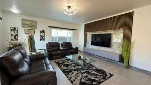 a living room with a leather couch and a television at Polokwane Luxury Guest House in Polokwane