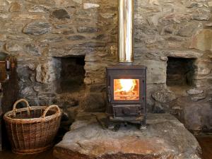 a wood stove in a stone wall with a basket at The Smiddy - S4278 in Lochearnhead