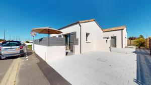 a white building with an umbrella in a parking lot at La Petite Vague in Saint-Gilles-Croix-de-Vie