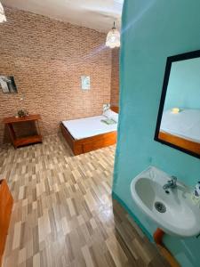 a bathroom with a sink and a bed and a mirror at Cebu - Victoria's Guest House in Badian