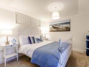 a bedroom with a white bed with a blue comforter at Lake View-Uk34414 in Cheddar