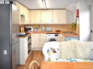 a kitchen with white cabinets and a refrigerator at Little Hog Cottage in Seaton +7 photos