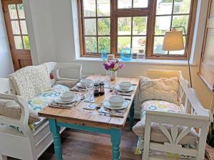 a dining room table with two chairs and a table with dishes on it at Little Hog Cottage in Seaton