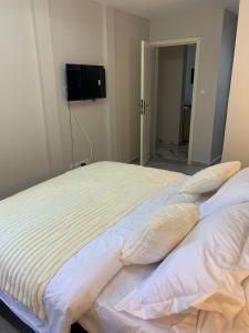 a large bed with pillows and a television on the wall at Modern 1bedroom apartment in Douala