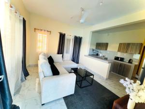 a living room with a white couch and a kitchen at The Wink apartments in Malindi