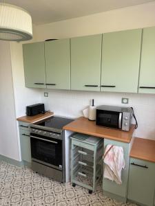 a kitchen with white cabinets and a counter with a microwave at Grand appartement dans une résidence à caen in Caen +8 photos