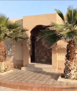 a building with two palm trees in front of it at Ezdan Residence إزدان رزيدينس in Unayzah
