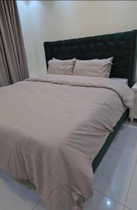 a large white bed with a green headboard at Ezdan Residence إزدان رزيدينس in Unayzah
