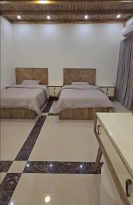 a bedroom with two beds and a checkered floor at Ezdan Residence إزدان رزيدينس in Unayzah