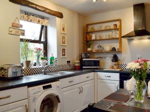 a kitchen with a sink and a washing machine at Park View Cottage in Old Glossop +4 photos