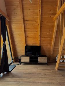ein Wohnzimmer mit Holzdecke und Fernseher in der Unterkunft Vlasic Odmor - Microcastl in Vlasic