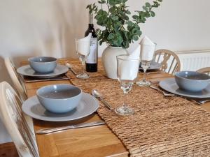 a table with plates and bowls and wine glasses at Y Dderwen At Brynglas Farm in Llanfair Caereinion