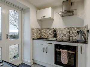 a kitchen with white cabinets and a stove top oven at Orchard View-Uk34417 in Cheddar