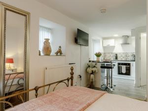 a bedroom with a bed and a mirror and a kitchen at Orchard View-Uk34417 in Cheddar