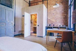 a room with a bed and a table and a brick wall at Old Post Loft Apartments in Spremberg