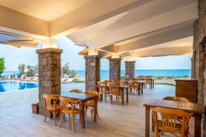 a restaurant with tables and chairs and the ocean at Cinarli Kasri in Gokceada Town
