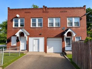 a brick house with two garages and a fence at Jefferson Carriage House Hideaway in Huntington