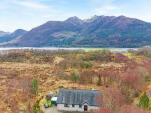 an aerial view of a house in a field with mountains at Nether Carness in North Ballachulish