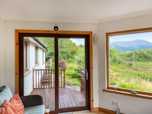 a living room with a sliding glass door with a view of a deck at Nether Carness in North Ballachulish