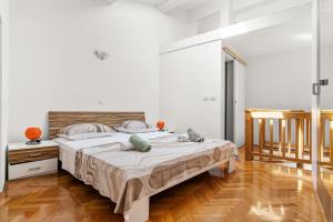 a white bedroom with a bed and a wooden floor at Apartment old Town in Lovran
