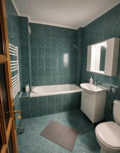 a bathroom with a tub and a toilet and a sink at Apartament Central in Moineşti
