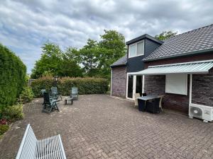 a patio with chairs and tables and a house at B&K het hoenveld in Driel