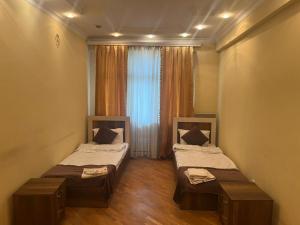 two beds in a small room with a window at Rahat Ev in Ganja