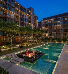 a pool at a hotel with people sitting around it at Zcape garden by lsqstays in Ban Rangeng