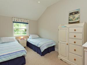 a bedroom with two beds and a dresser and a window at Eddystone Row 2 in Salcombe +16 photos